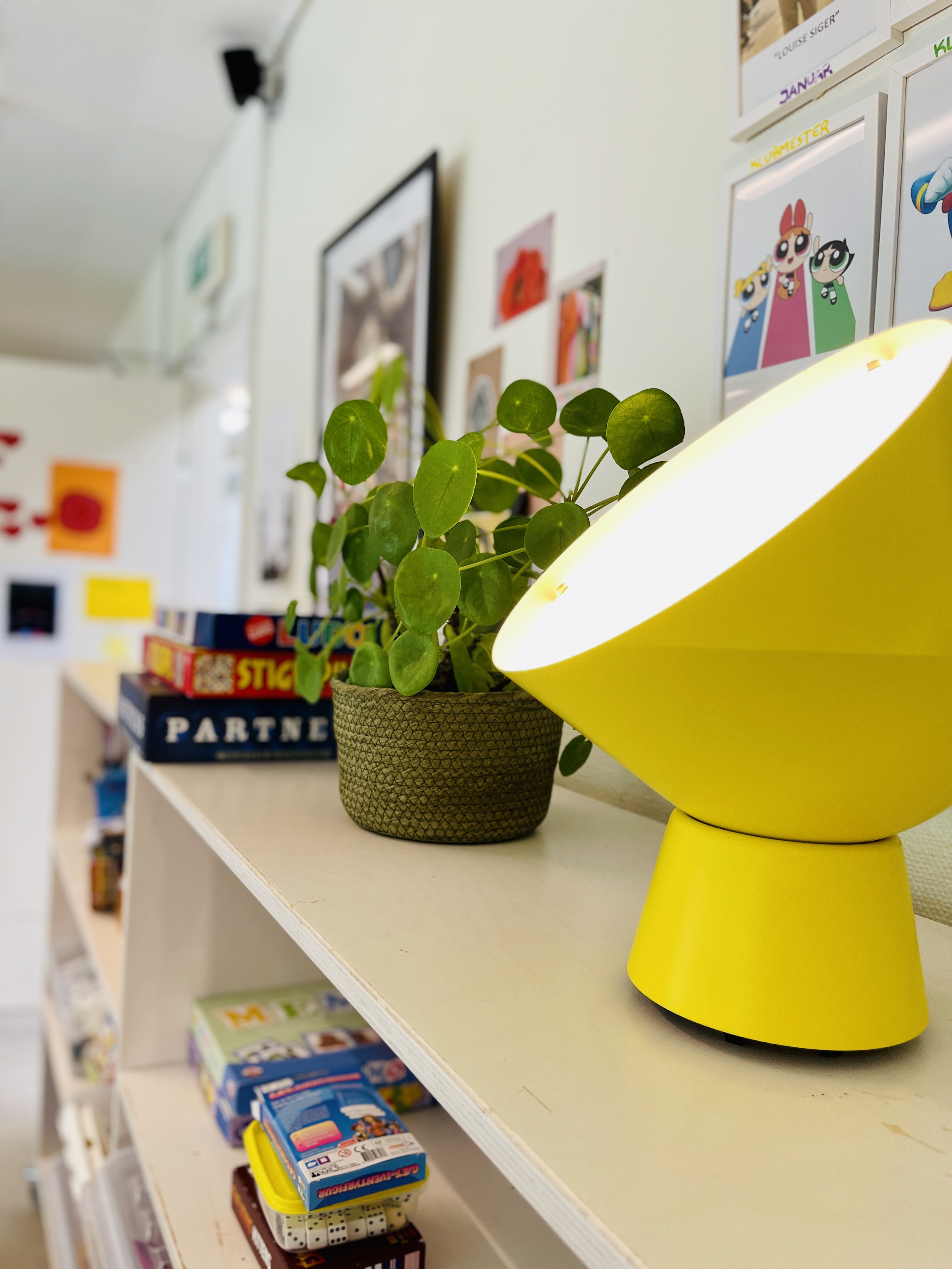 gul lampe og plante på reol