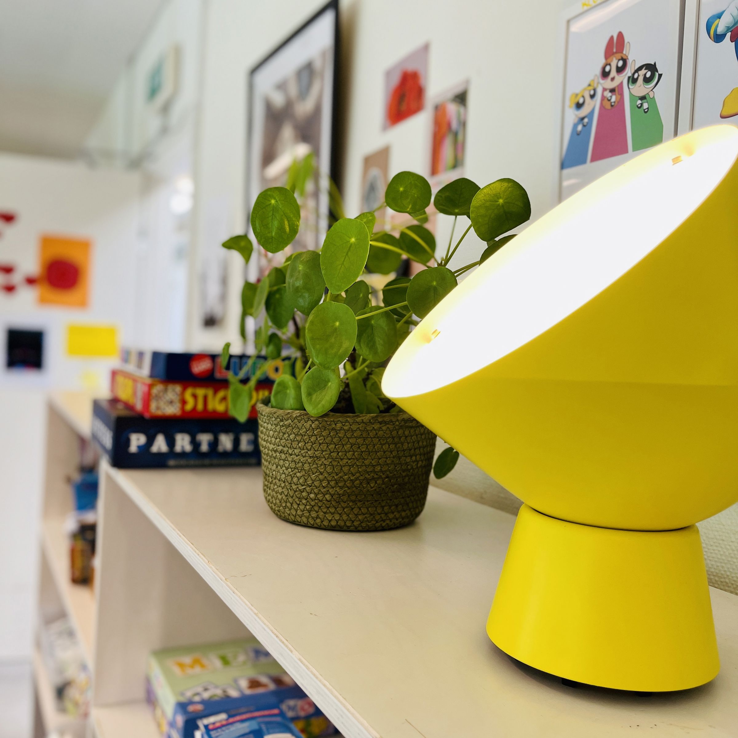 gul lampe og plante på reol