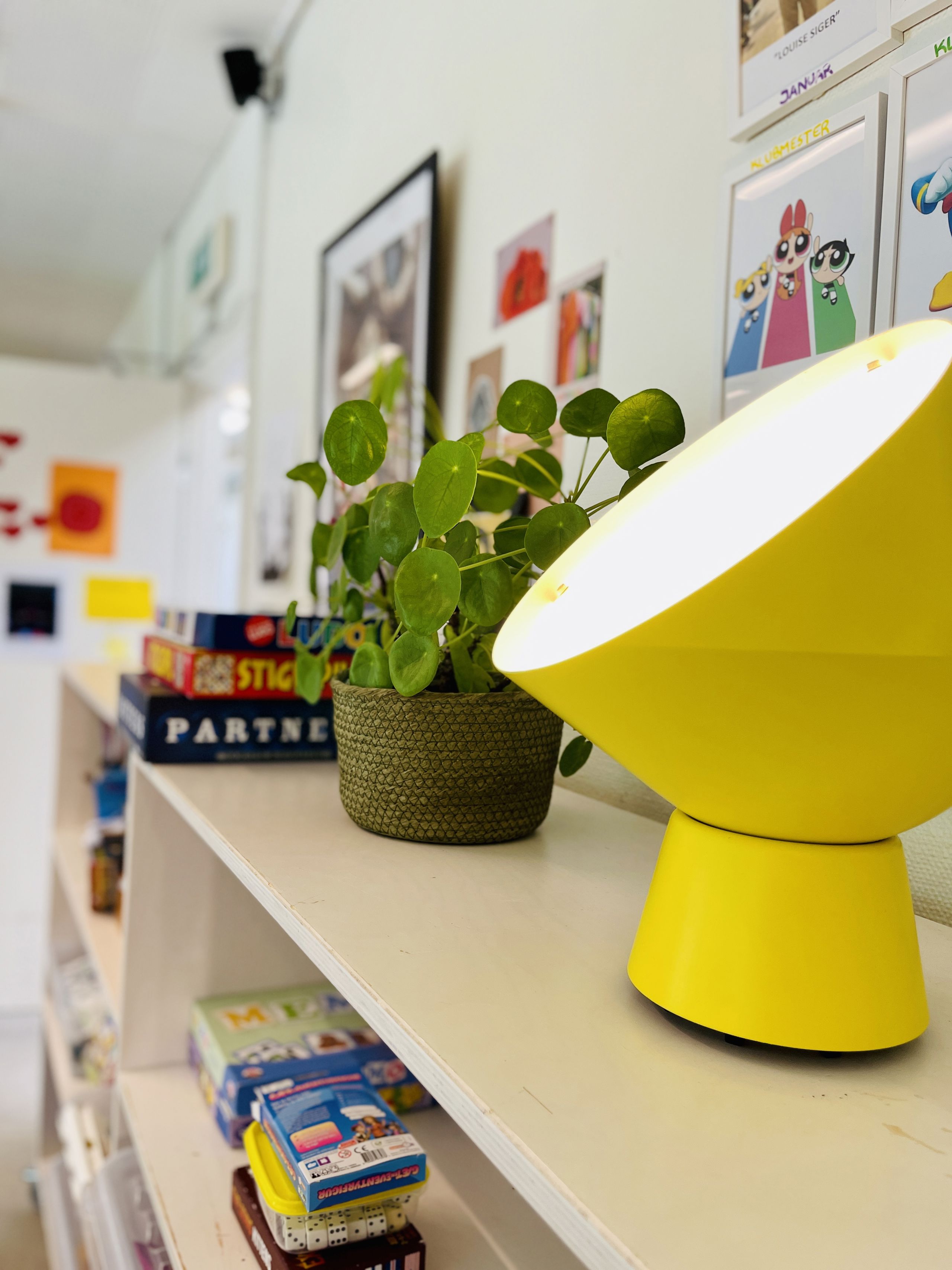 gul lampe og plante på reol