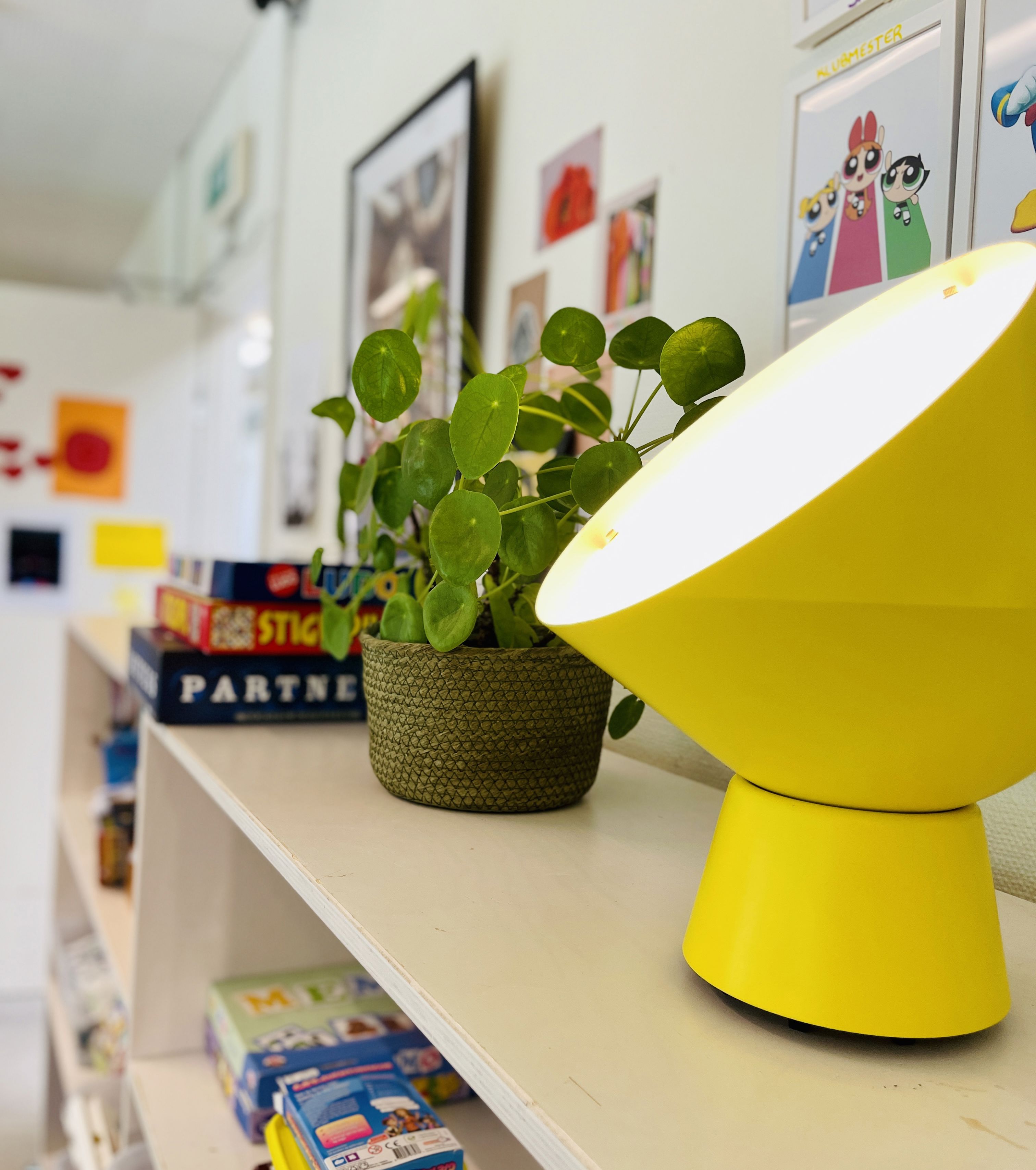 gul lampe og plante på reol